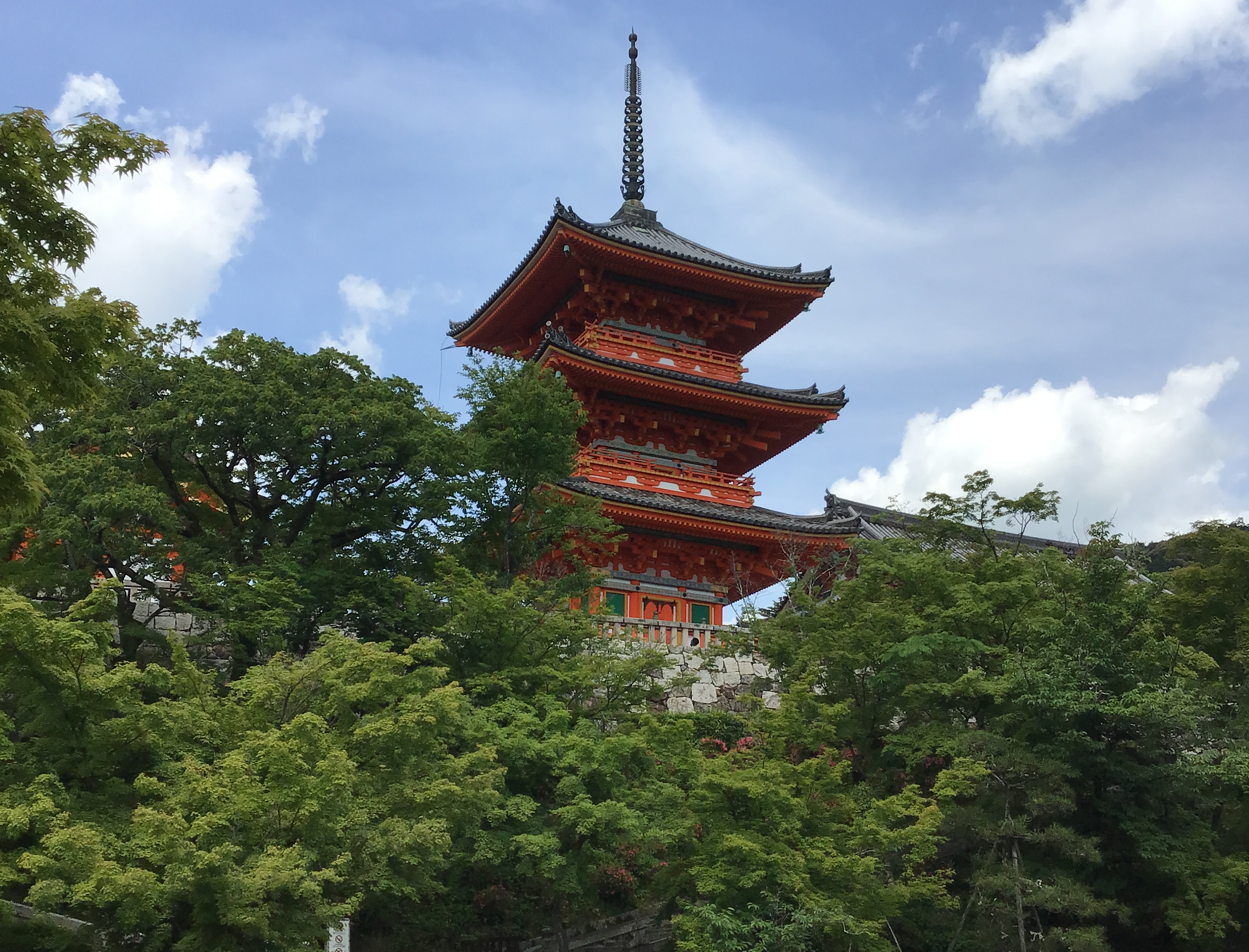 A red pagoda behind a screen of trees